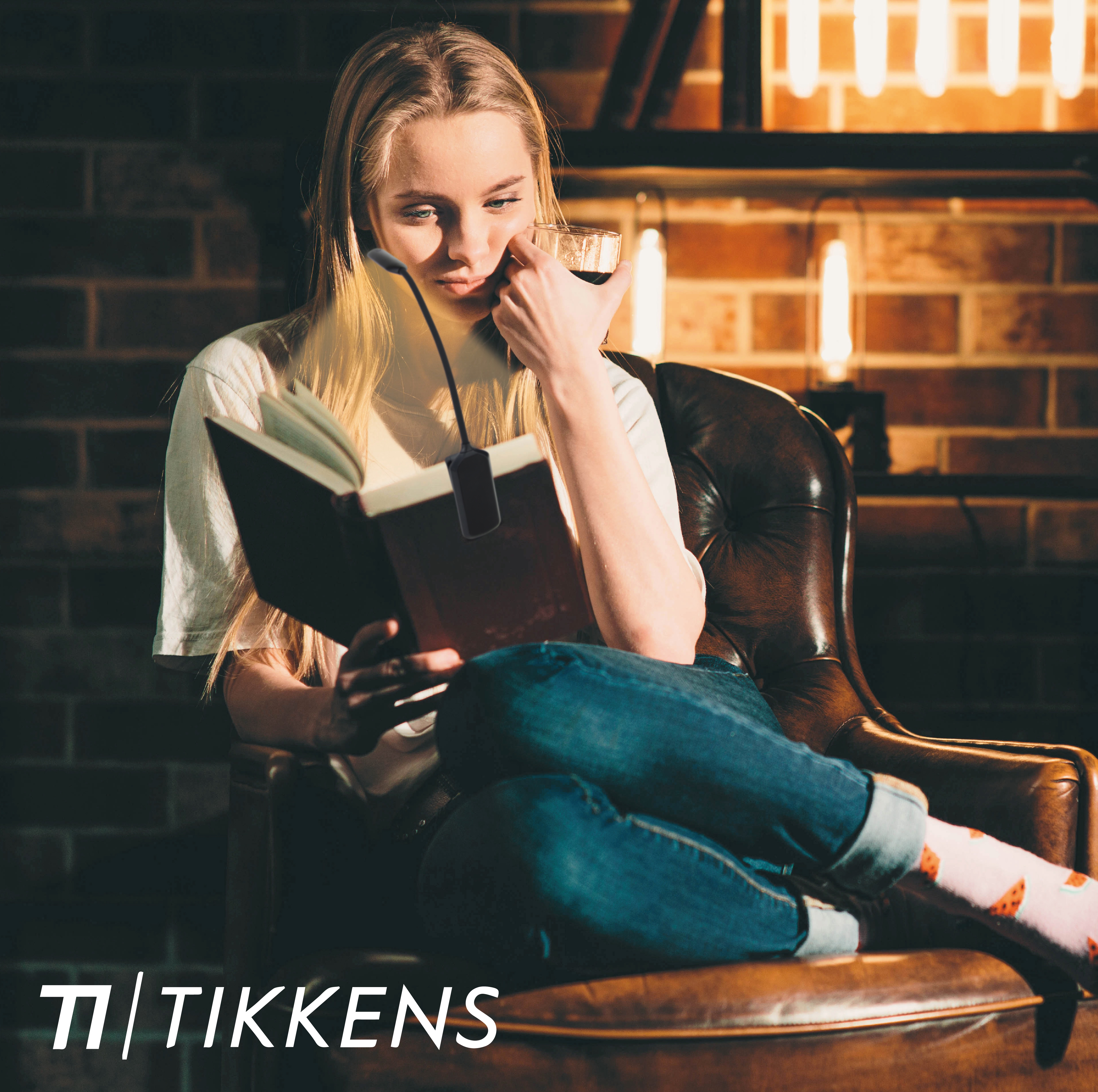 Een jonge vrouw zit in een leren fauteuil en leest een boek.