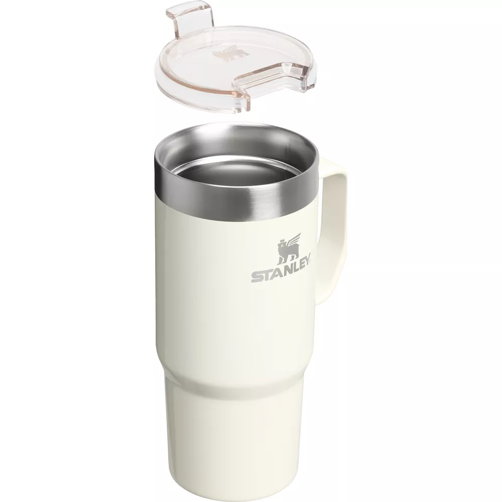 Eine cremefarbene Stanley-Tasse mit Griff und abnehmbarem durchsichtigem Deckel.