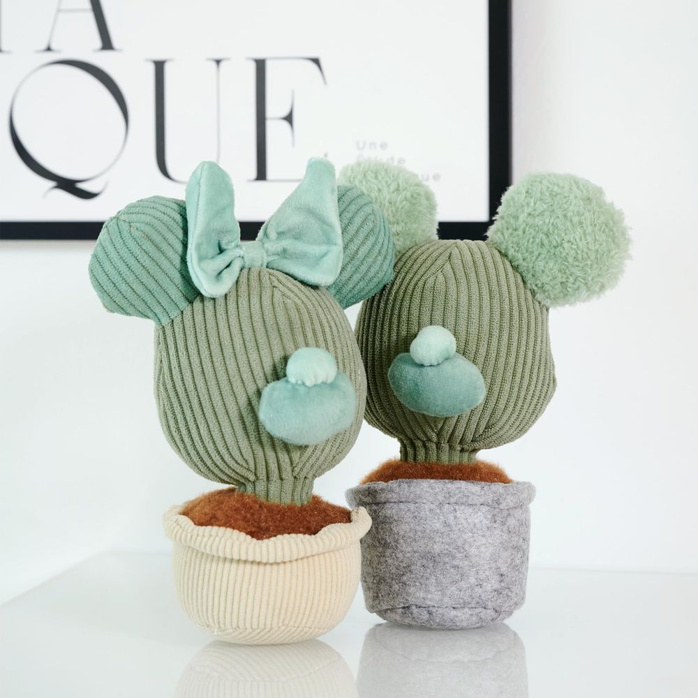 Deux peluches cactus tricotées avec des oreilles de Mickey dans des pots sur une table.
