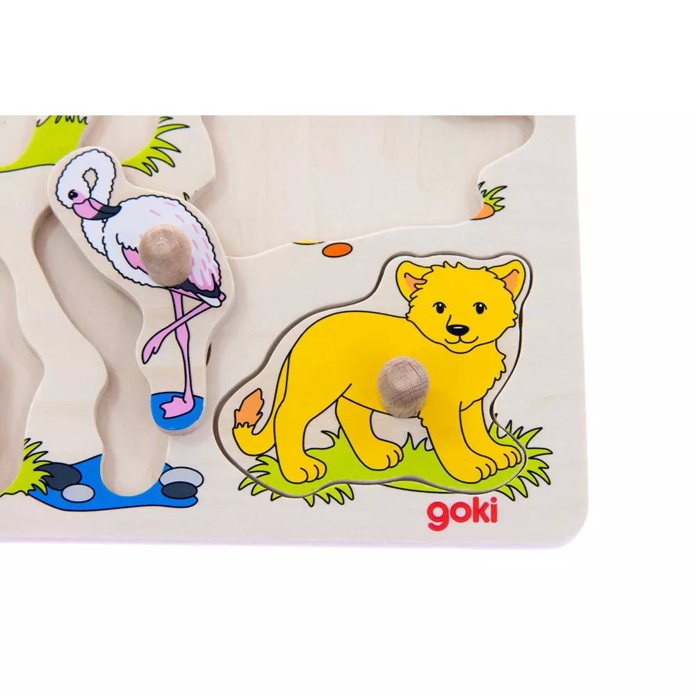 Ein Holzpuzzle mit einem gelben Löwen und einem rosa Flamingo auf einer grünen Wiese.