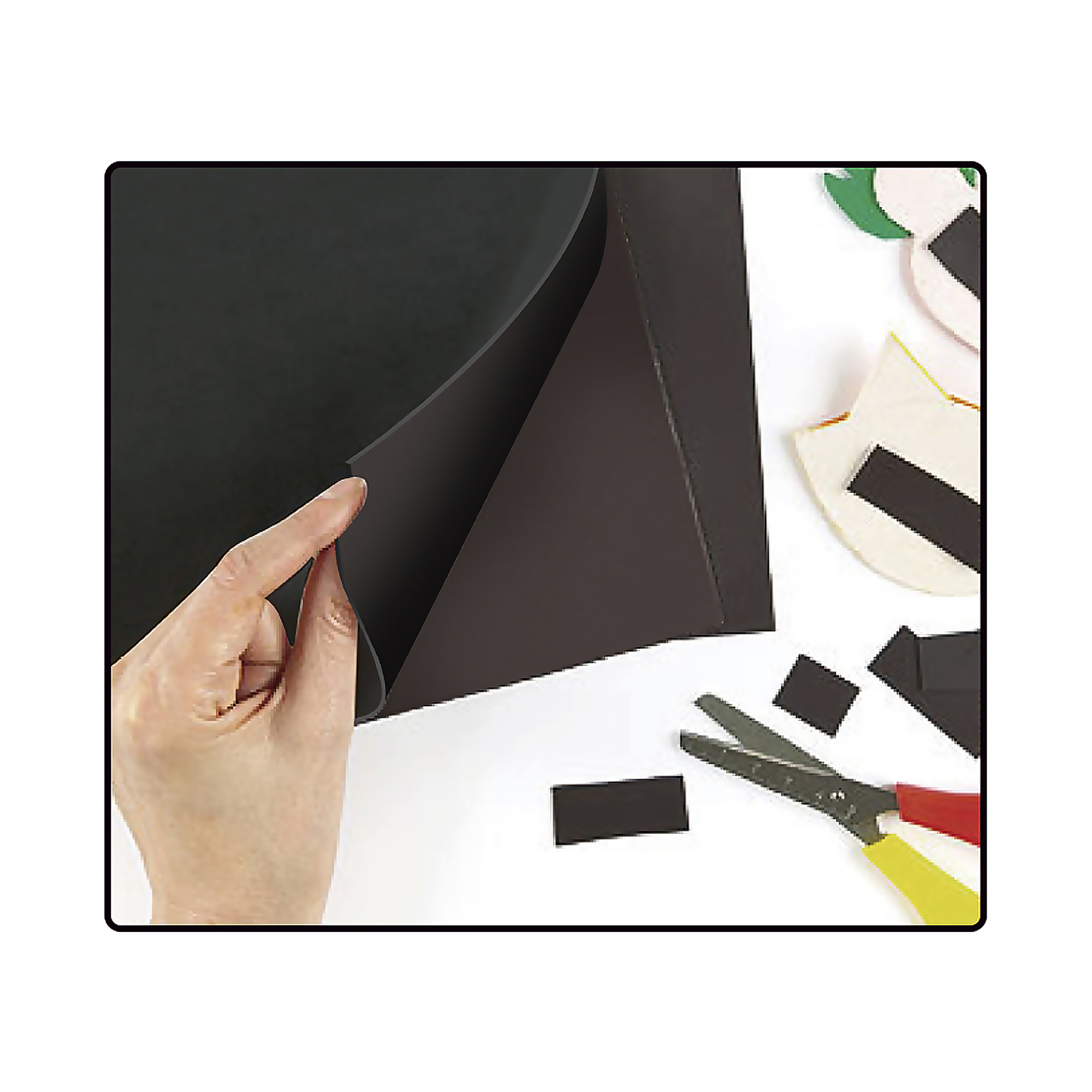 Mano che tiene nastro magnetico nero, forbici e pezzi magnetici nelle vicinanze.