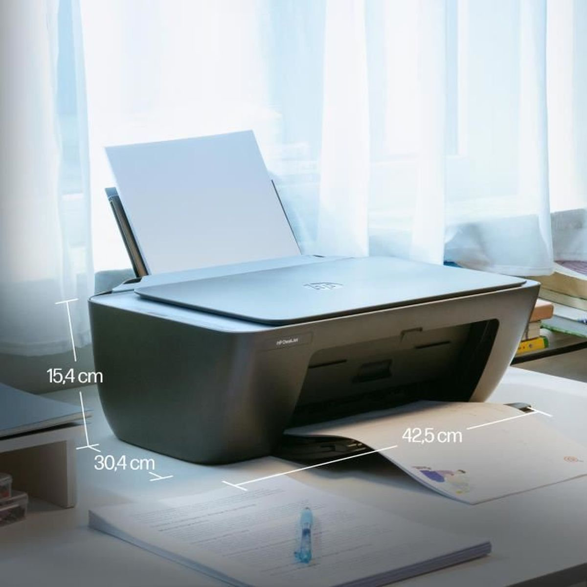 Ein grauer HP Drucker steht auf einem Schreibtisch mit Papier und Büchern.