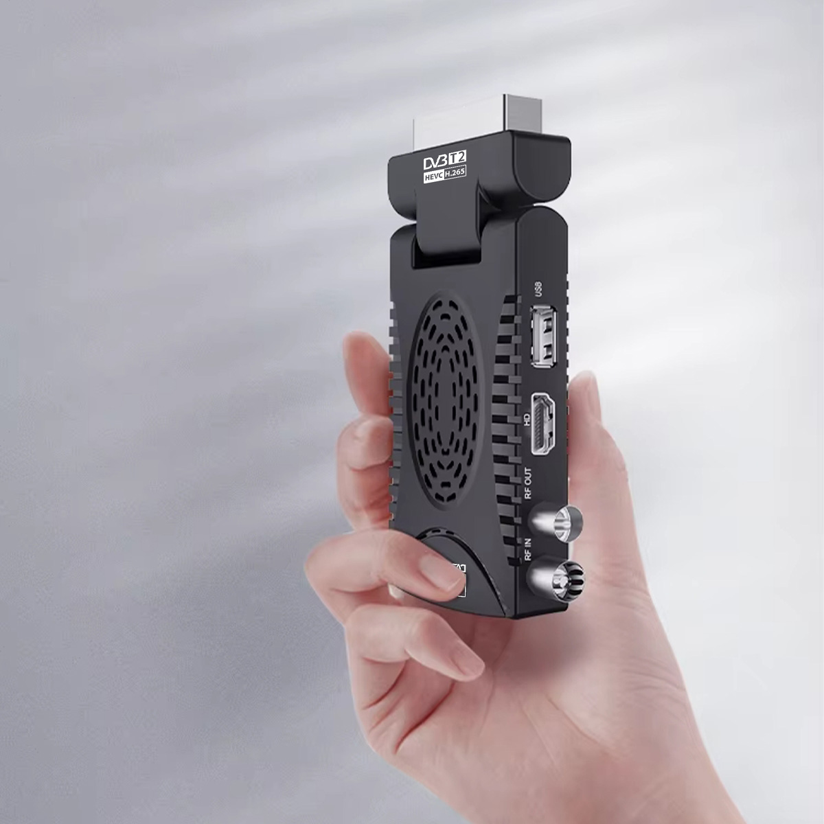 Dłoń trzyma czarny odbiornik DVB-T2 z portami HDMI, USB i RF.