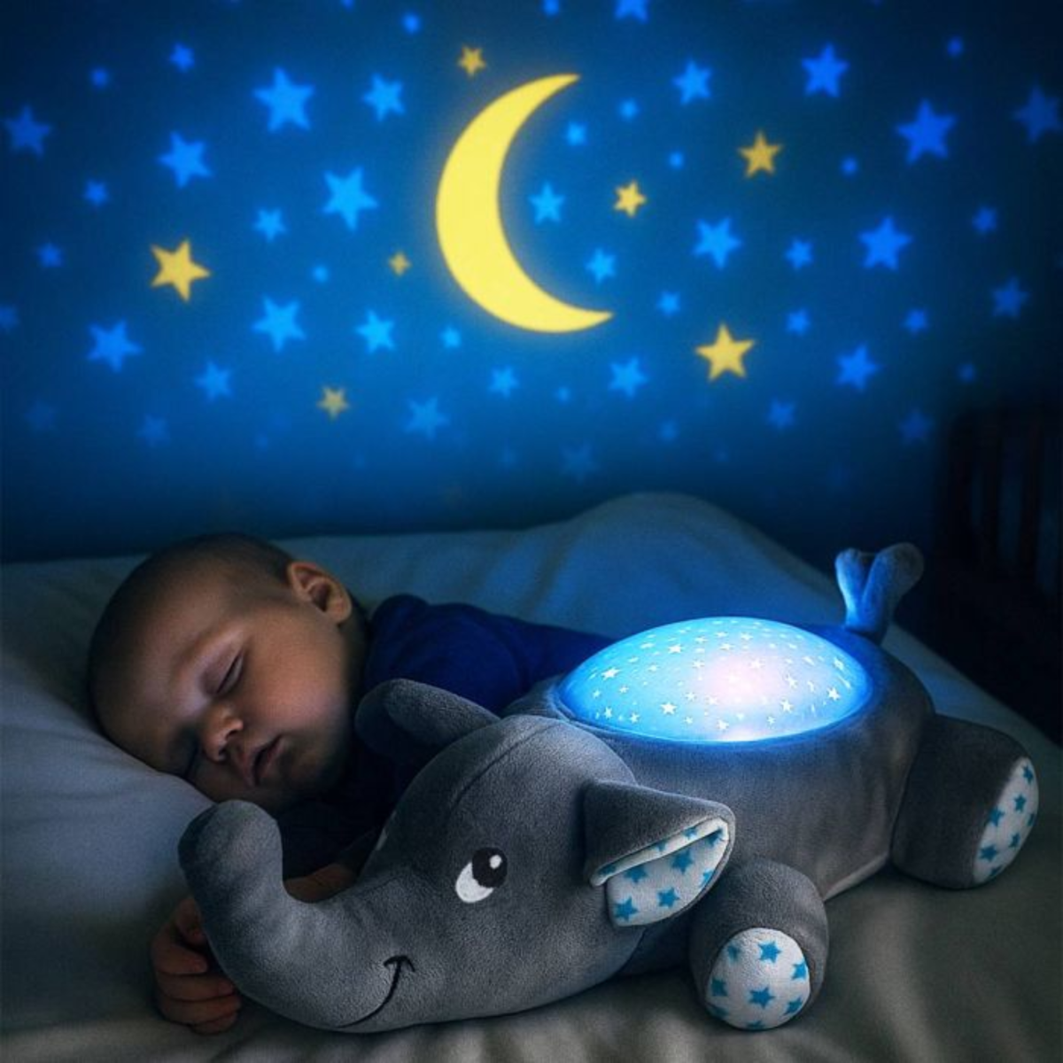 A baby sleeps next to a star-patterned elephant night light.