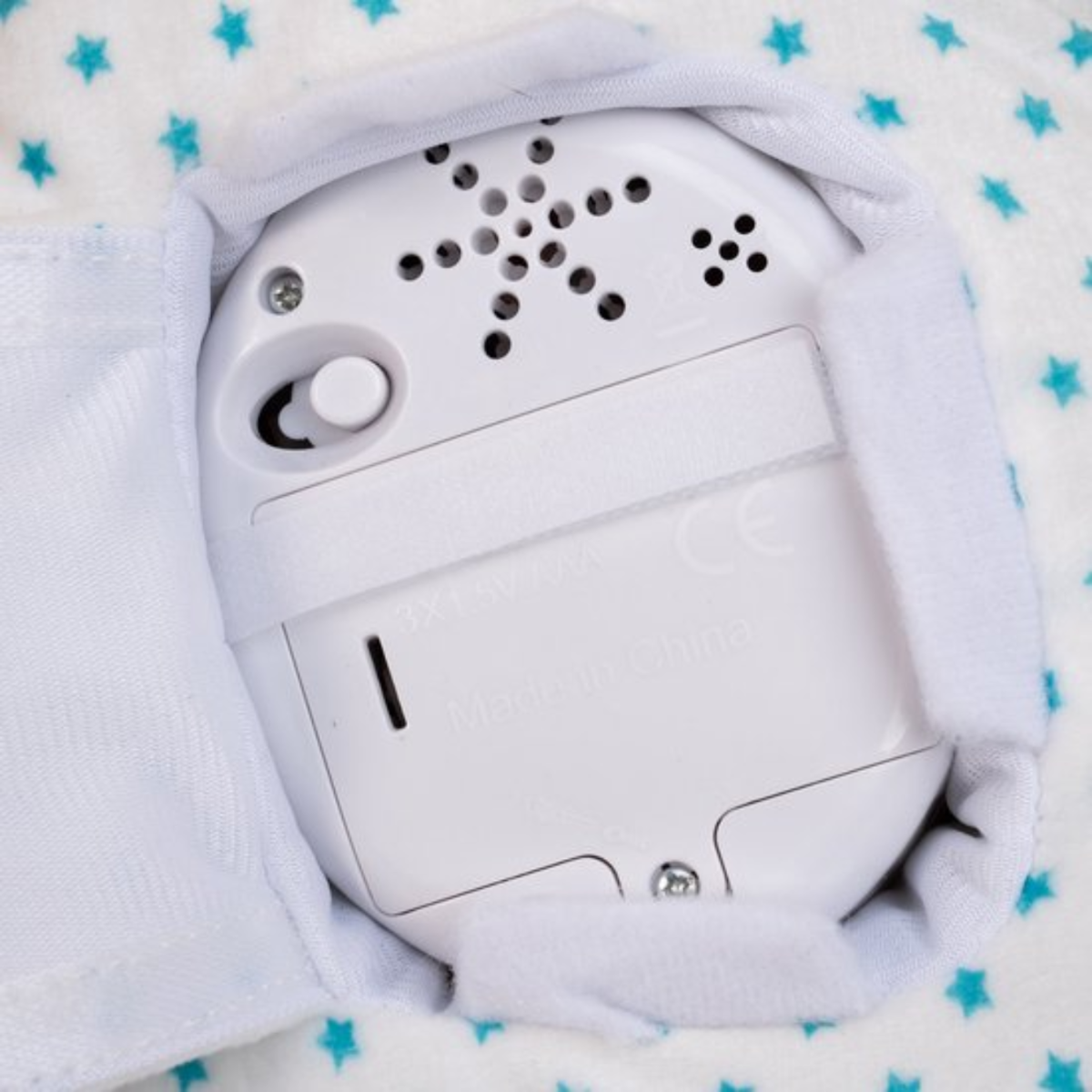 Close-up of device with speaker and switch on starry fabric.
