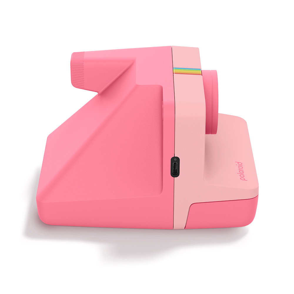 Eine pinke Polaroid Sofortbildkamera mit einem Regenbogenstreifen-Detail ist von der Seite zu sehen.