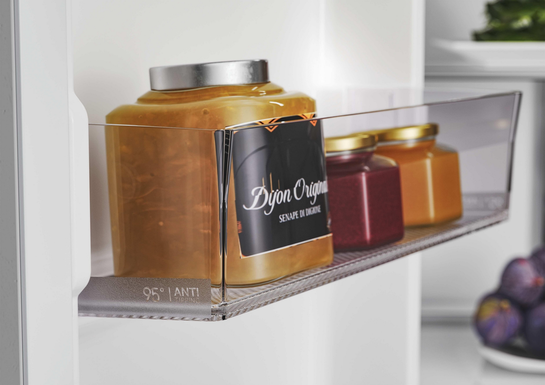 Barattoli di senape e marmellata su uno scaffale del frigorifero, con frutta in basso.