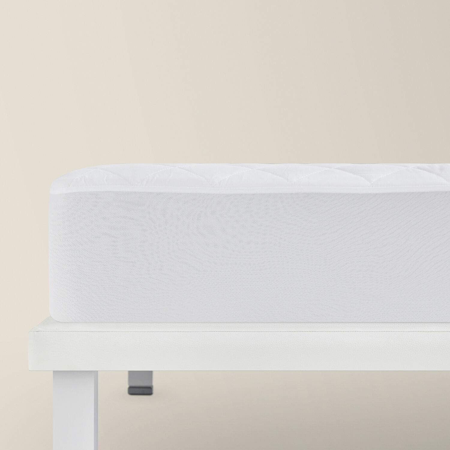 Un colchón blanco acolchado descansa sobre un marco de cama blanco.
