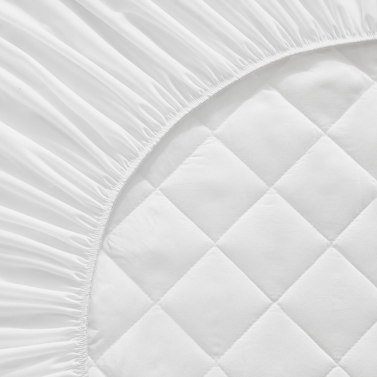 Ropa de cama blanca con elástico y superficie acolchada de rombos.