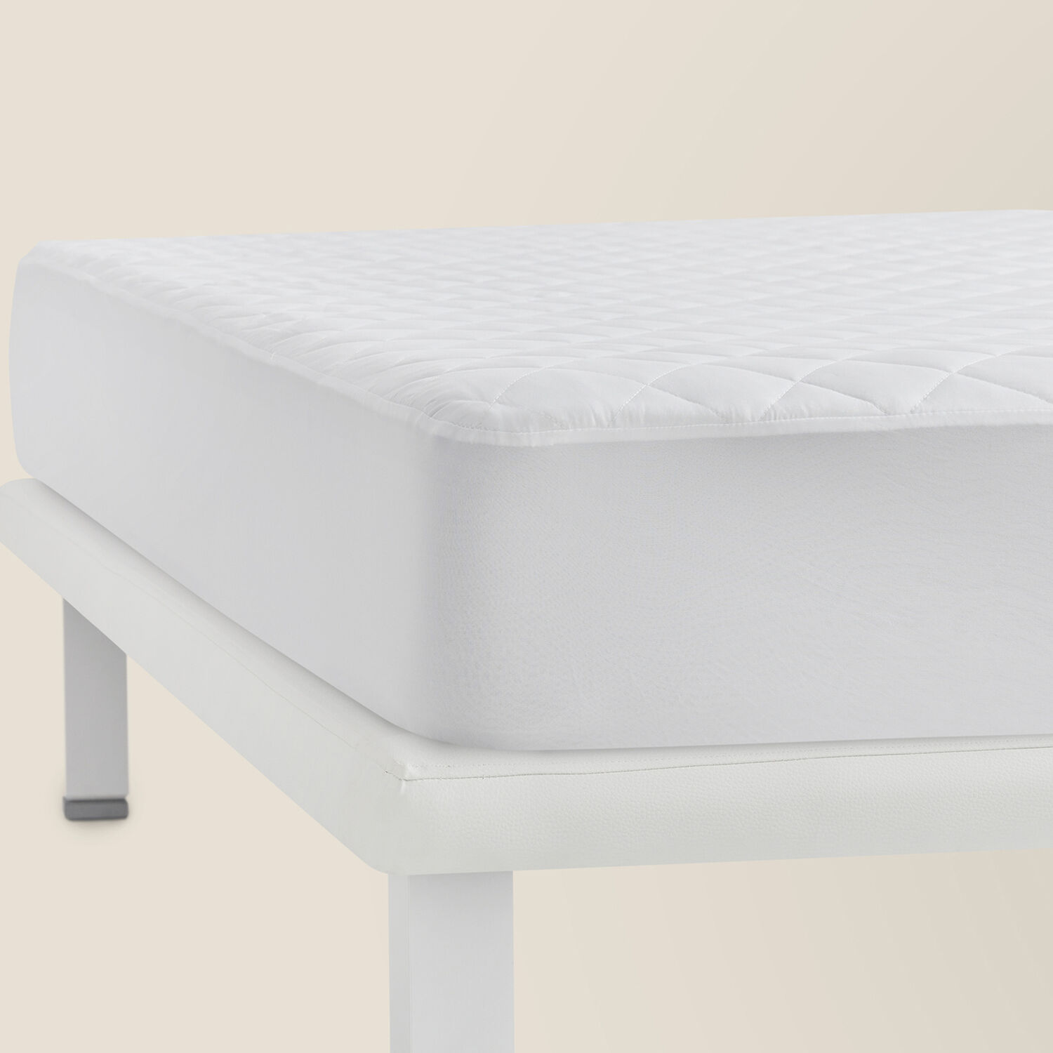 Funda de colchón blanca acolchada sobre un somier blanco.