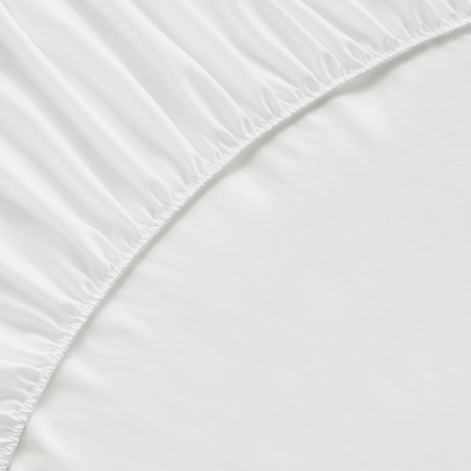 Primer plano de una esquina de sábana bajera blanca con elástico.