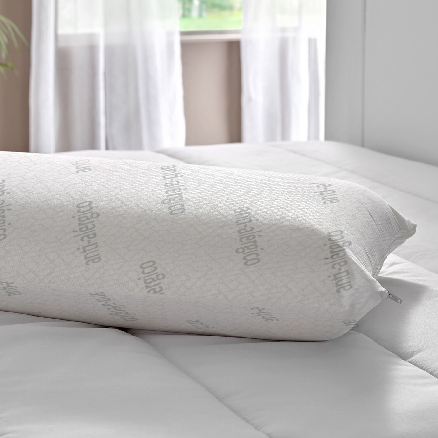 Una almohada blanca con estampados antialérgicos grises descansa sobre una cama.