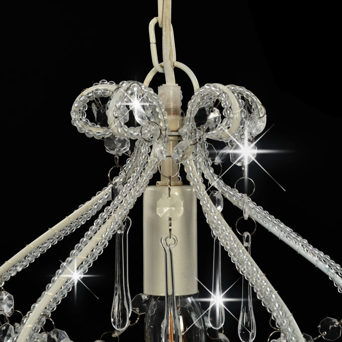 Eine weiße Lampe mit Kristalltropfen und Perlen, die an einem schwarzen Hintergrund hängt.