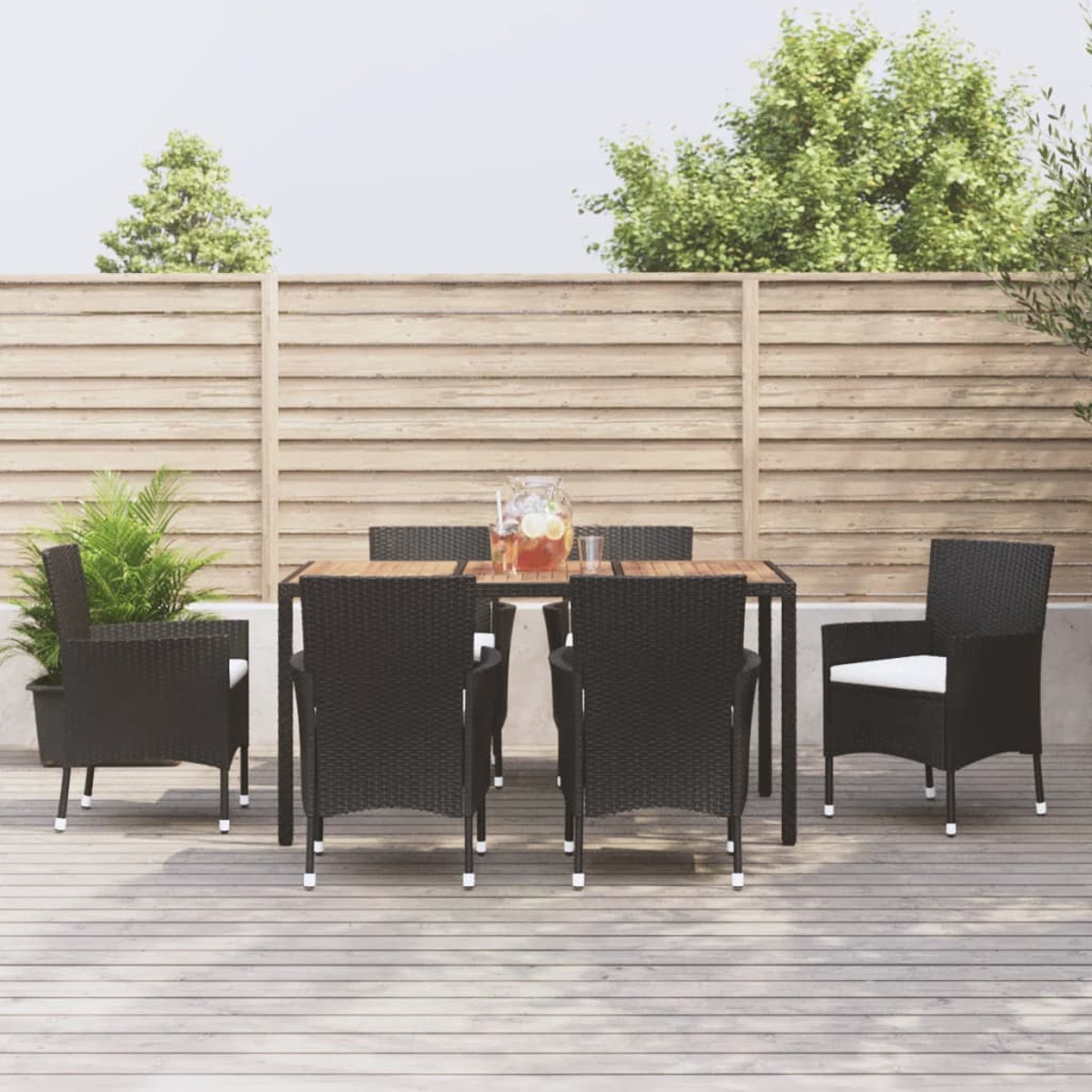 Gartentisch mit sechs schwarzen Stühlen und einem Krug mit Getränk.