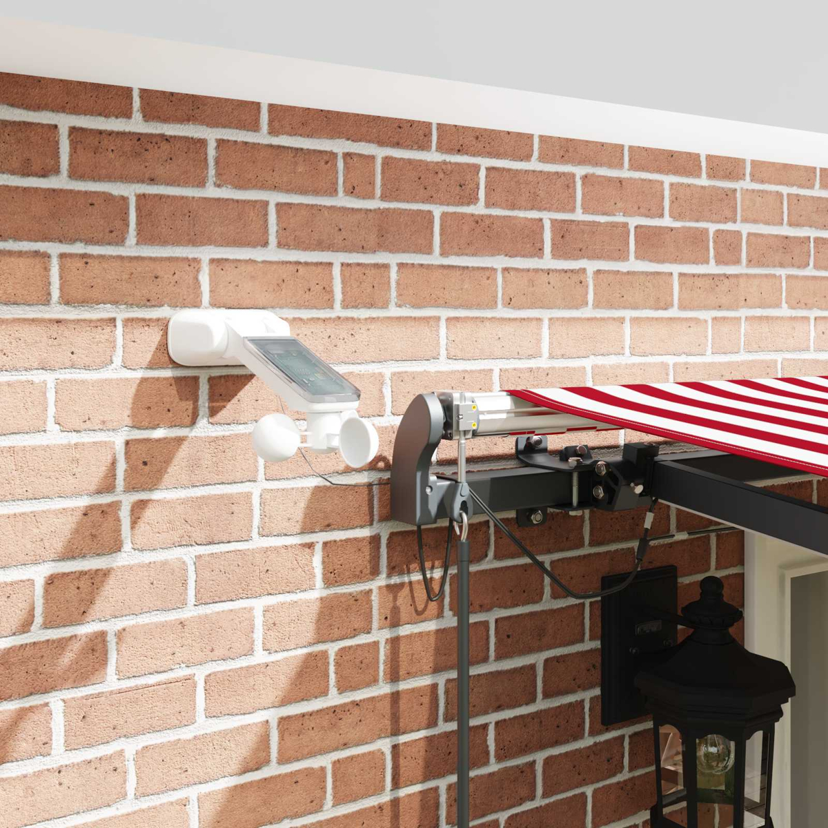 Un sensor meteorológico blanco con panel solar y dos esferas en pared de ladrillos junto a toldo.
