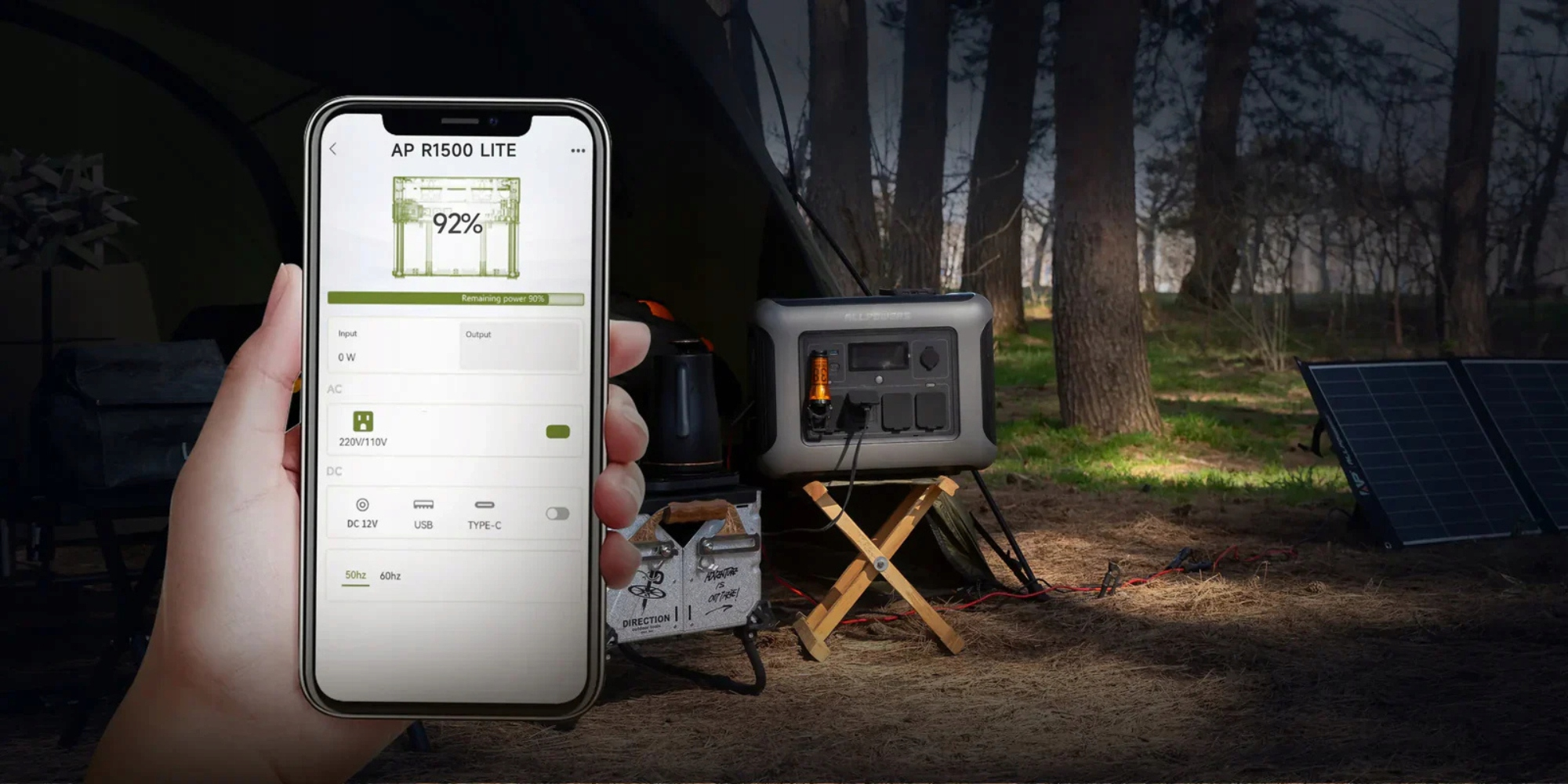 Dłoń trzyma telefon z wyświetlaczem ładowania. Generator prądu w lesie z panelem słonecznym.