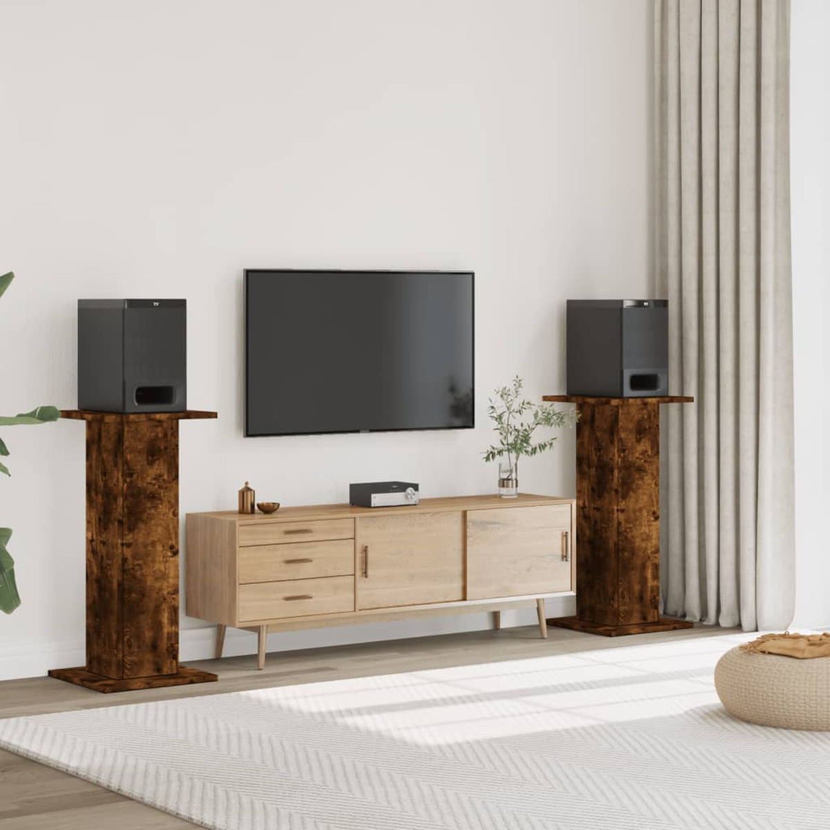Schwarze Lautsprecher auf braunen Holzständern vor einem Fernseher und einem Sideboard.