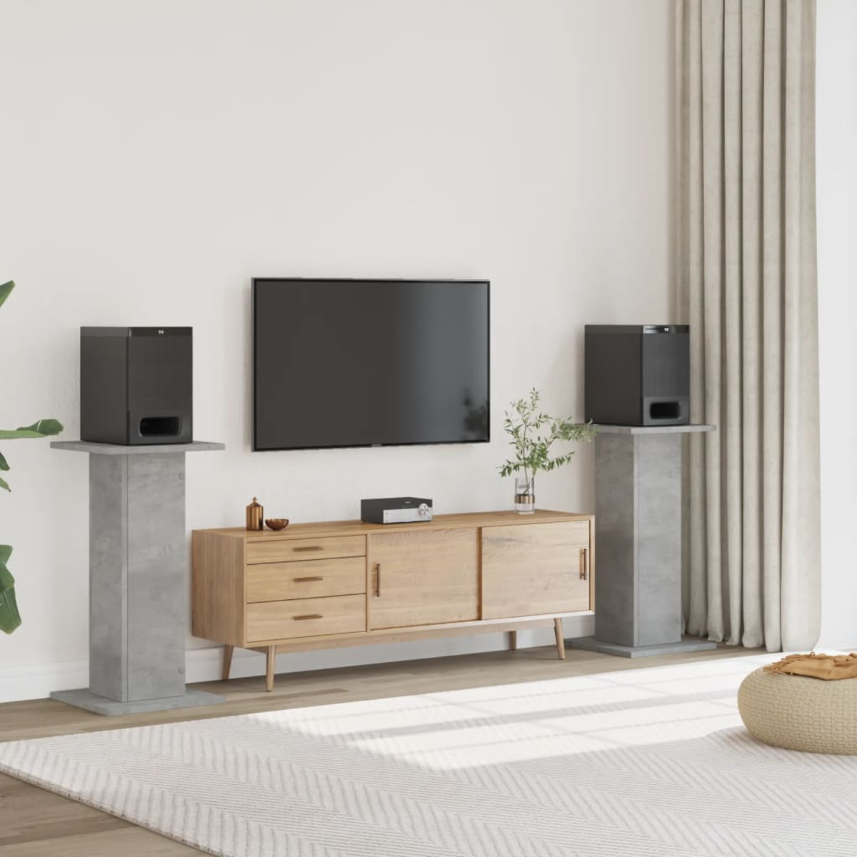 Ein schwarzer Fernseher hängt über einem Holzschrank mit Lautsprechern auf Sockeln daneben.