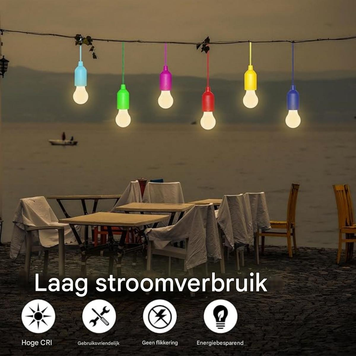 Lichterkette im Freien mit bunten Glühbirnen über Tischen und Stühlen.