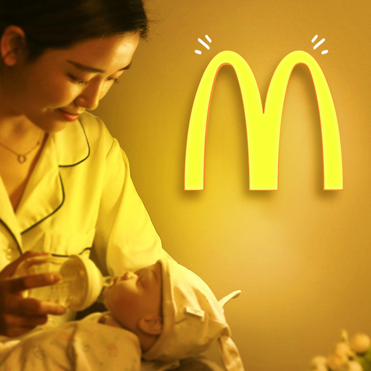 Eine Frau füttert ein Baby mit einer Flasche vor einem McDonald's-Logo.