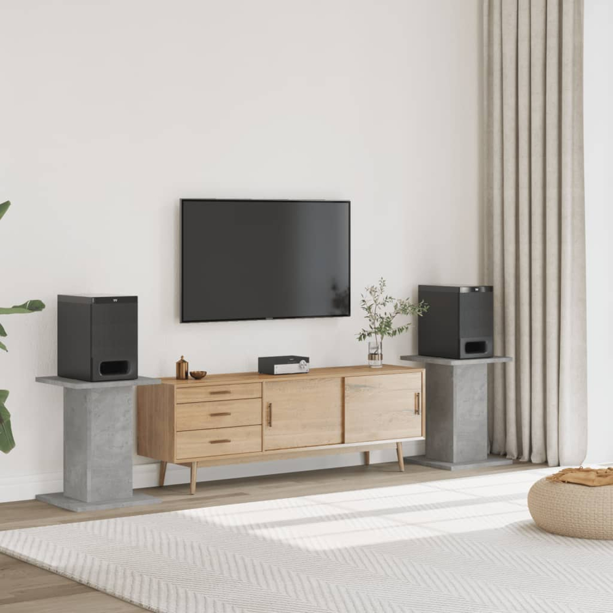 Ein Wohnzimmer mit einem Fernseher, einem TV-Schrank, zwei Lautsprechern und einem Teppich.