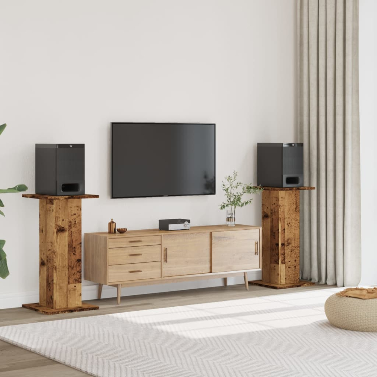 Ein Wohnzimmer mit Fernseher, Sideboard, zwei Lautsprechern auf Holzständern und einem Teppich.