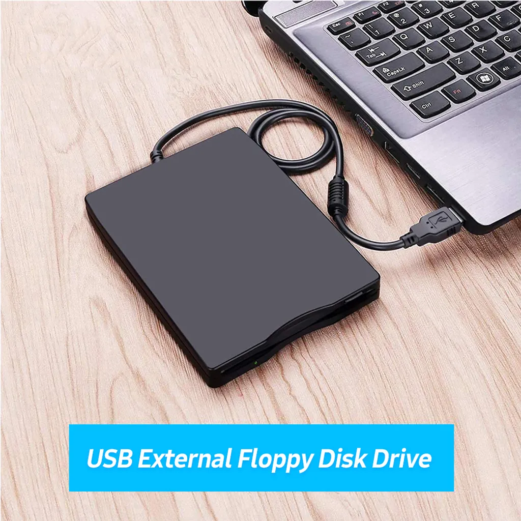 Ein schwarzes externes USB-Diskettenlaufwerk ist an einen Laptop auf einem Holztisch angeschlossen.