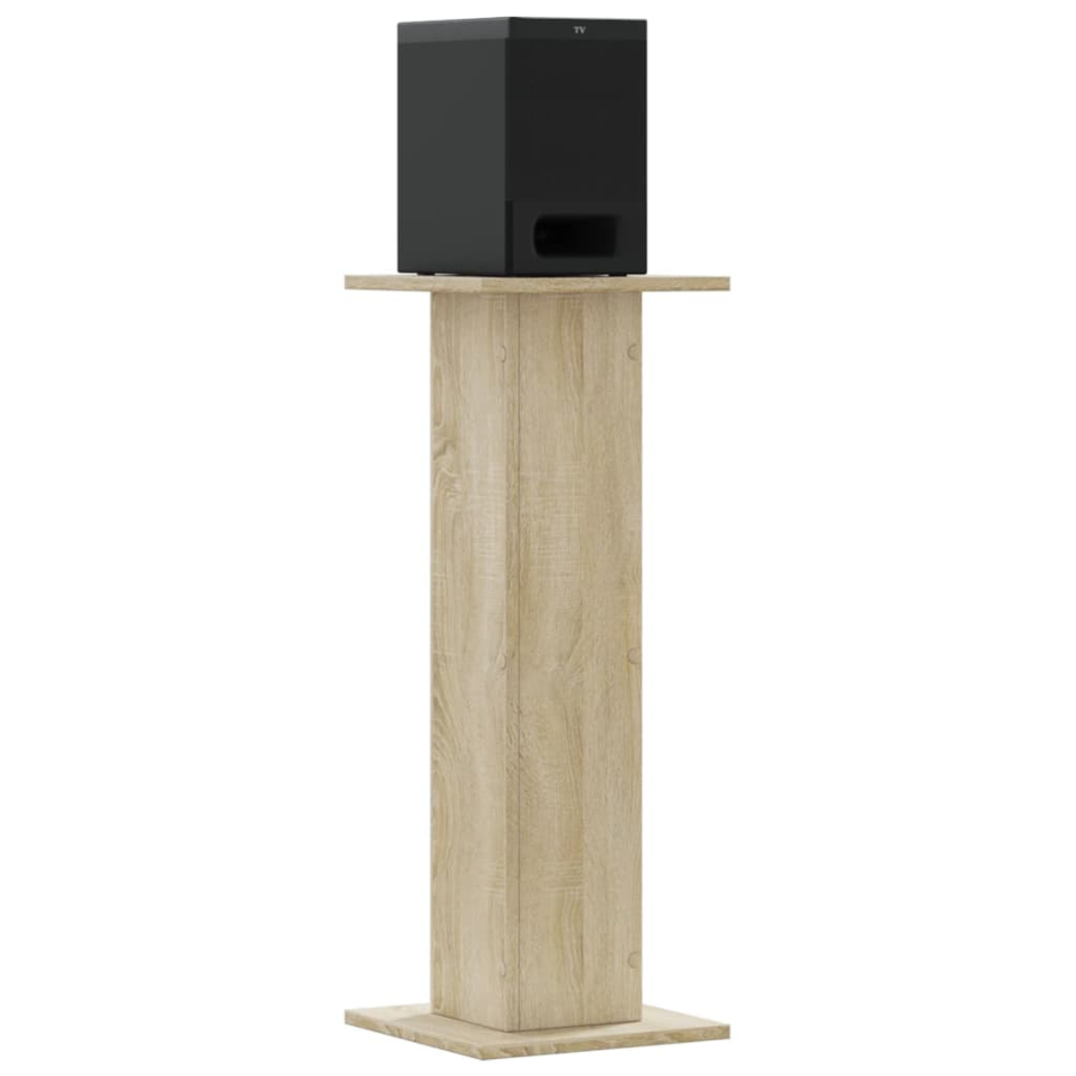 Ein schwarzer Subwoofer steht auf einem hellen Holzsockel vor weißem Hintergrund.