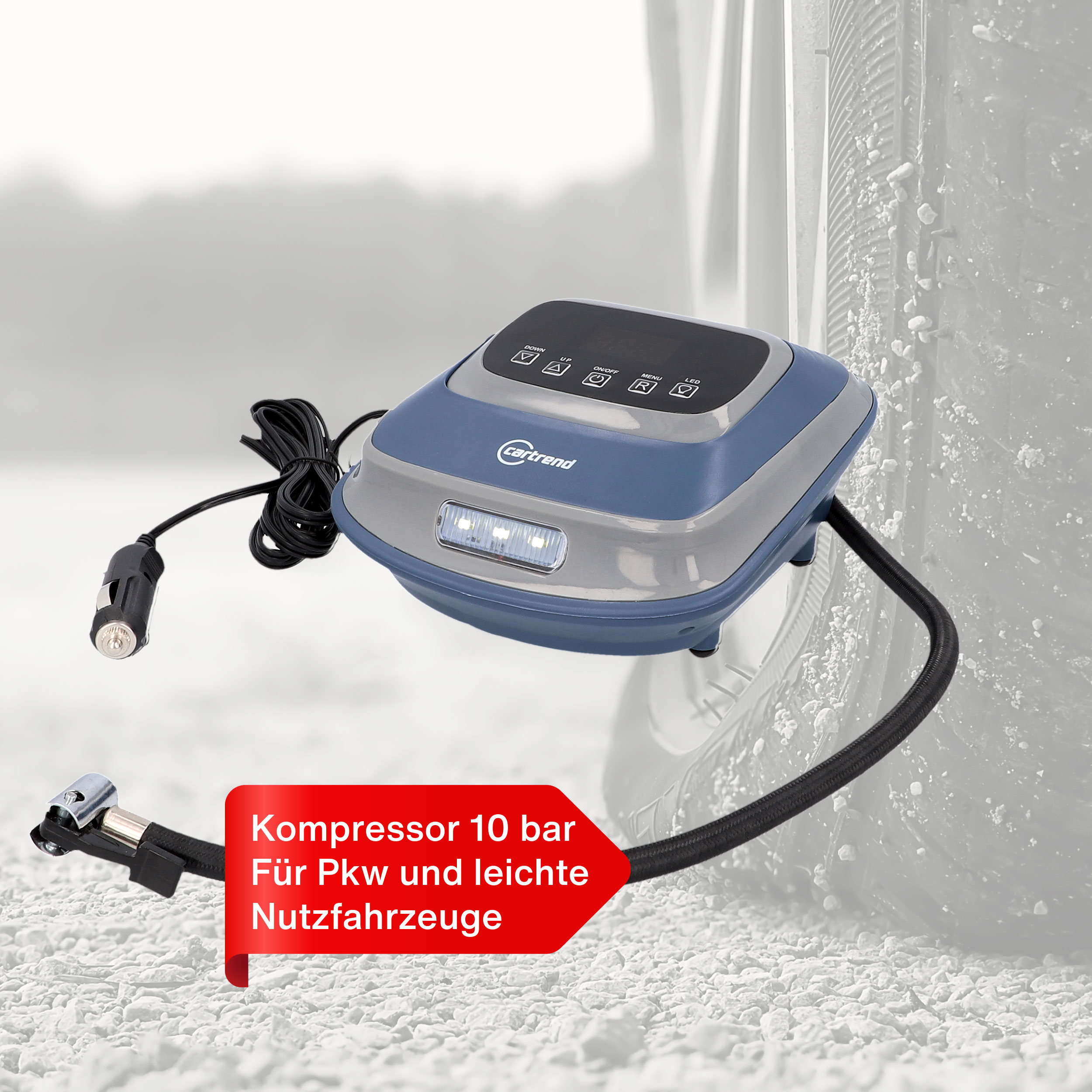Ein blauer und grauer Reifenkompressor mit Schlauch und Kabel auf Schotter.