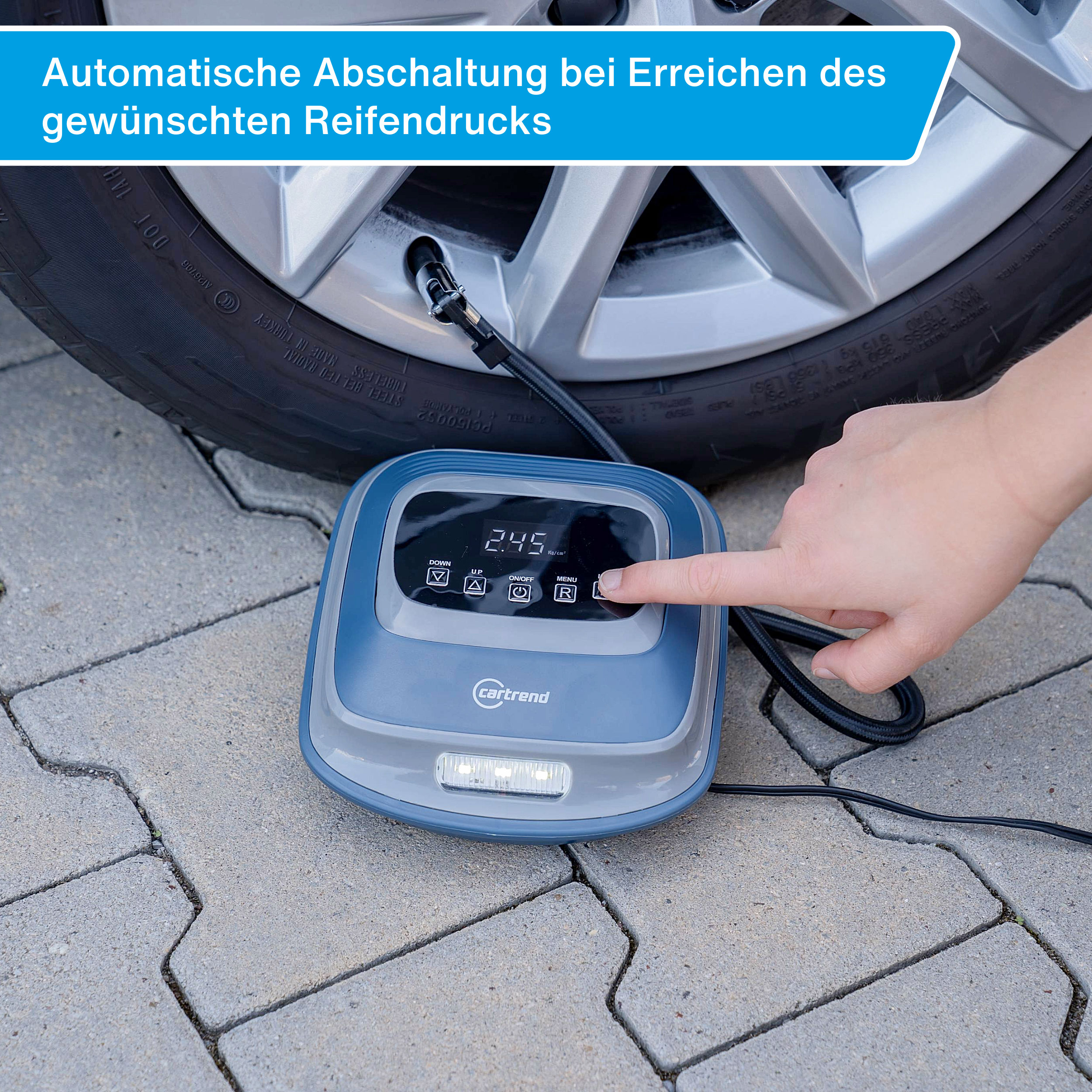 Eine Hand bedient einen Reifenfüller, der an ein Auto angeschlossen ist.