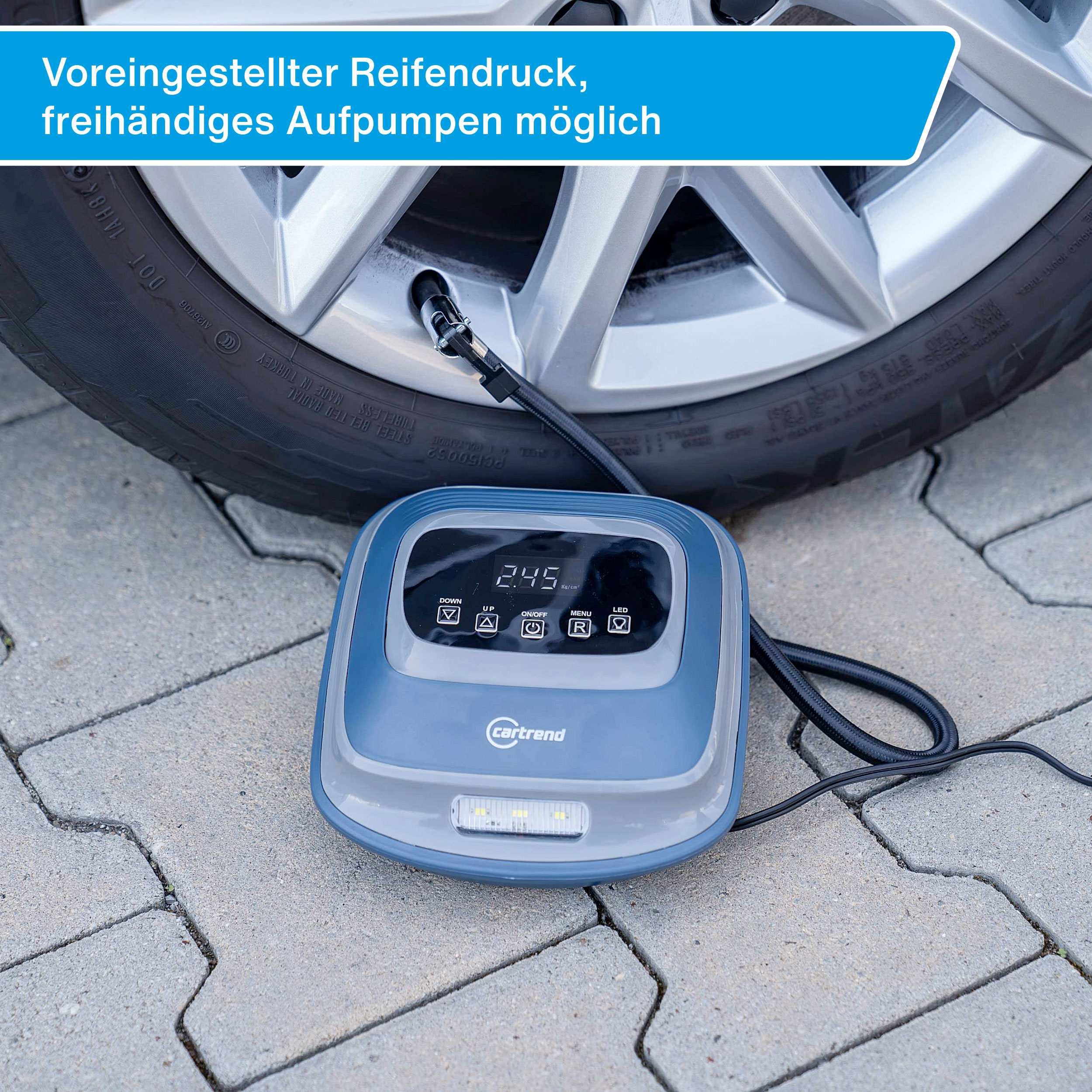 Ein tragbarer Reifenfüller mit LCD-Display neben einem Autoreifen.