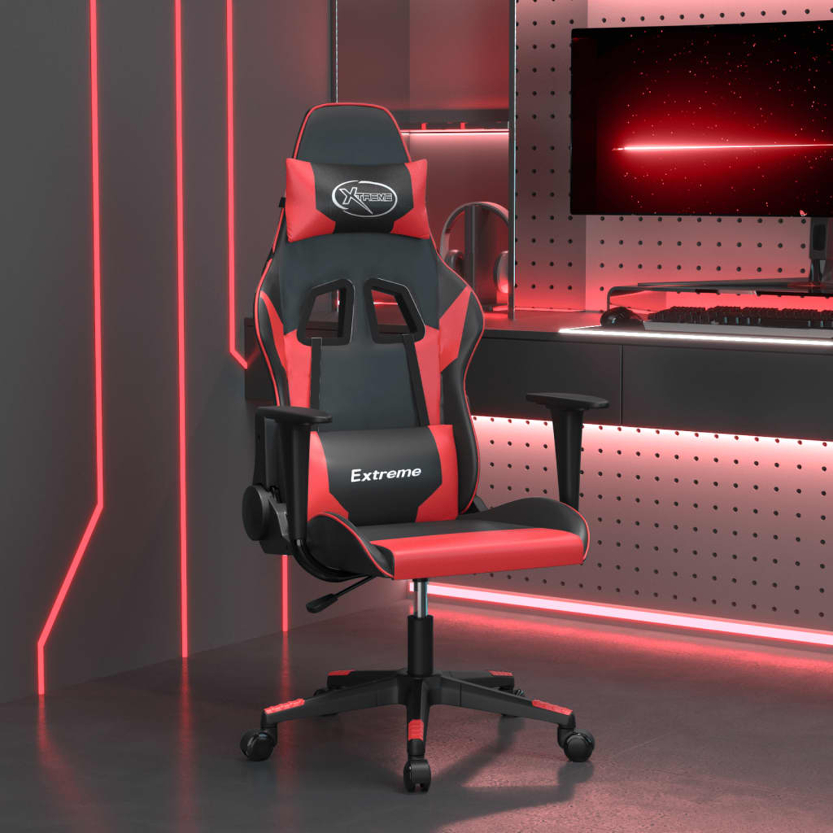 Ein roter und schwarzer Gaming-Stuhl mit Kissen, der vor einem Schreibtisch mit Monitor steht.