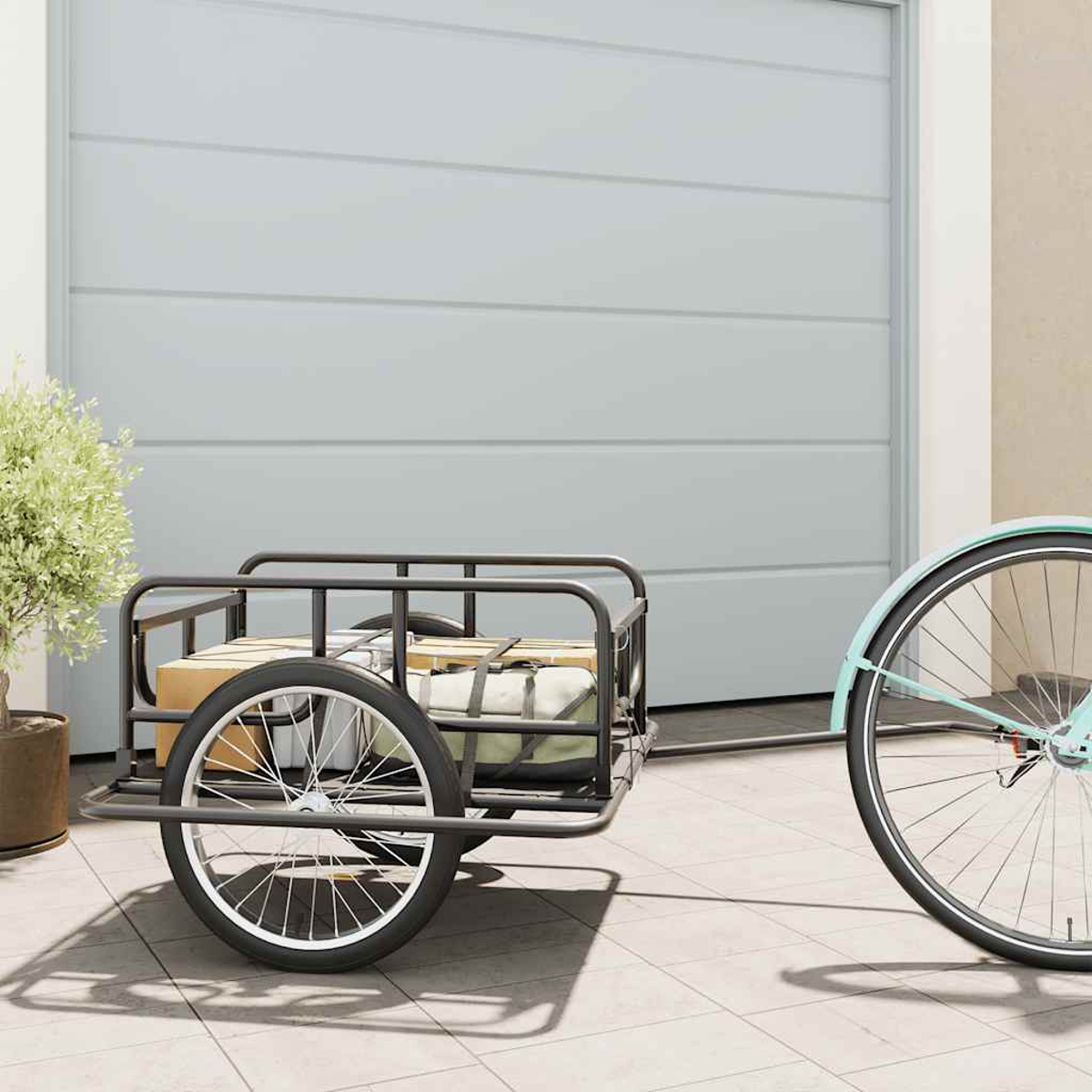 Ein Fahrradanhänger mit Gepäck steht neben einem Fahrrad vor einem Garagentor.