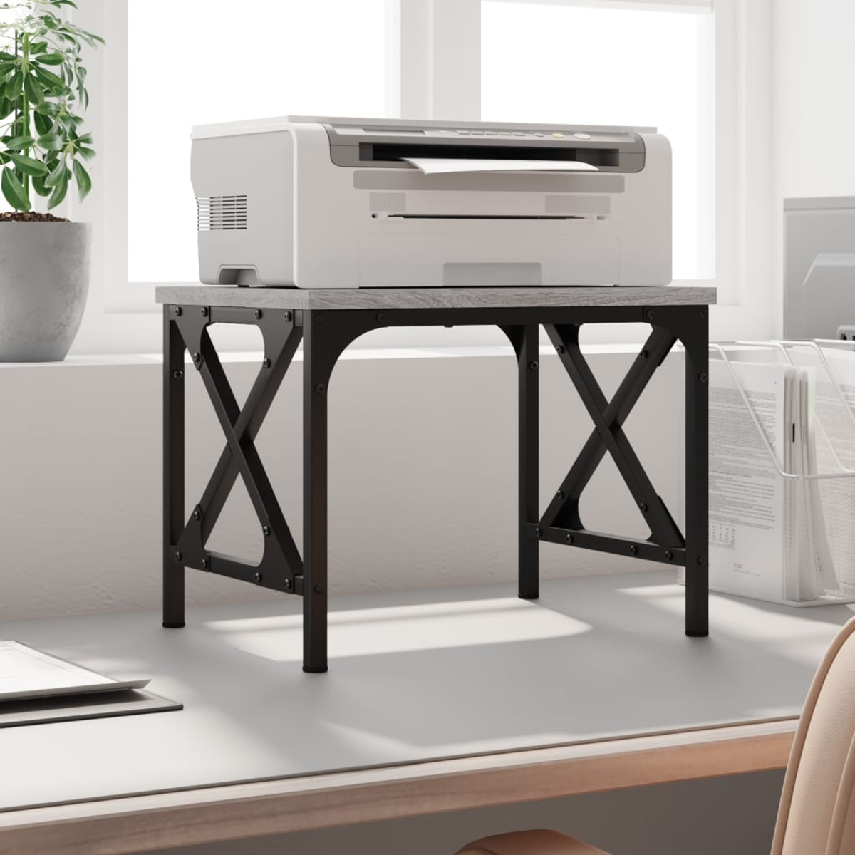 Ein Drucker steht auf einem kleinen grauen Tisch mit schwarzen Metallbeinen.