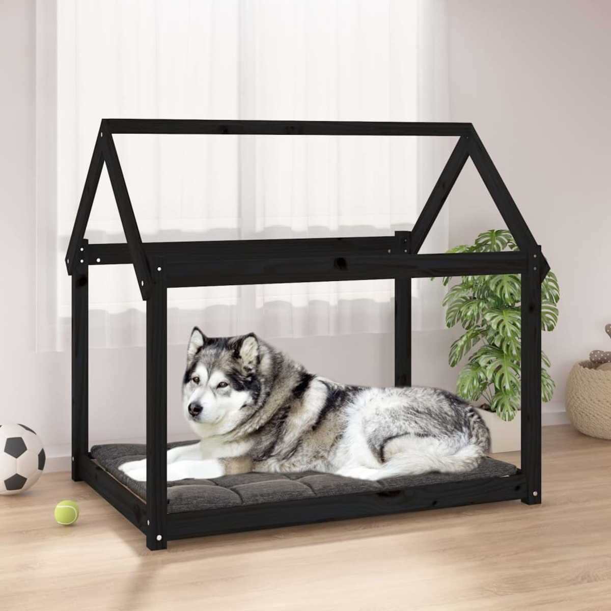 Ein Husky-Hund liegt auf einem Kissen in einem schwarzen Hundebett im Hausstil.