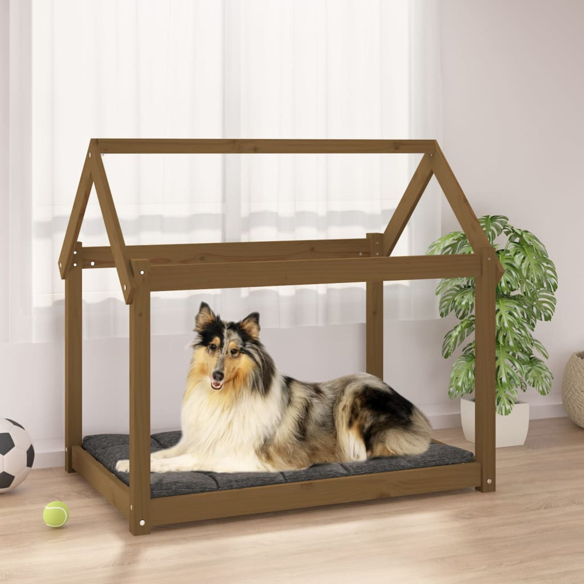 Ein Collie liegt auf einem Hundebett in Hausform mit dunklem Kissen.