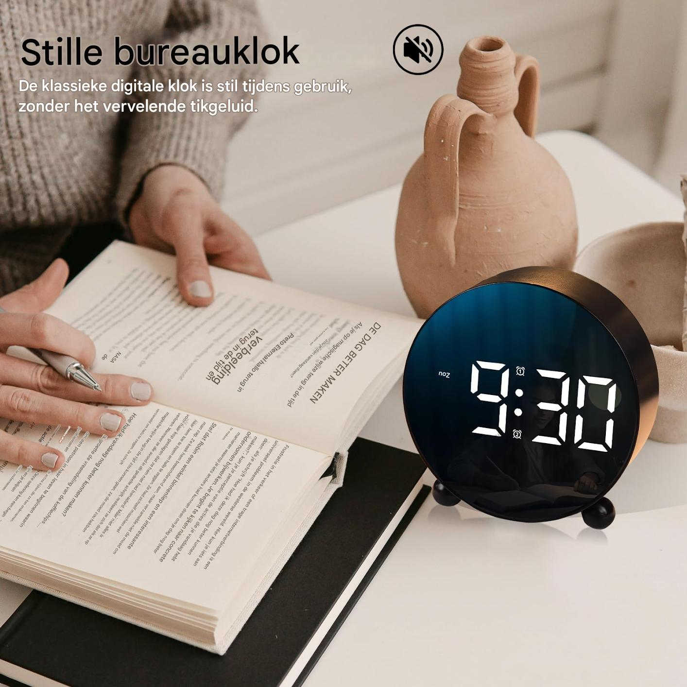 Ein Buch, ein Wecker mit digitaler Anzeige und eine Vase auf einem Tisch.