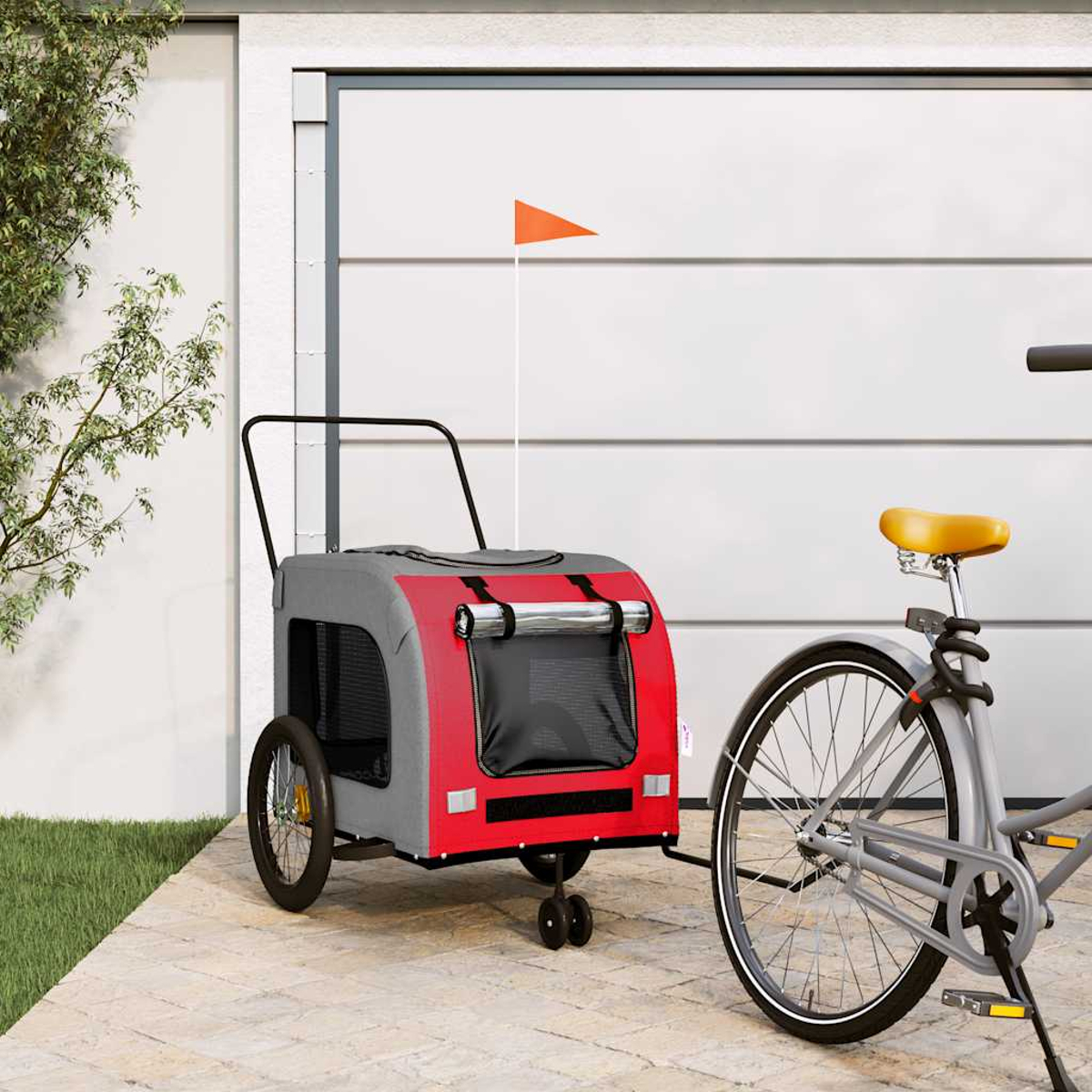 Ein rot-grauer Haustieranhänger mit orangefarbener Flagge ist an ein Fahrrad angehängt.
