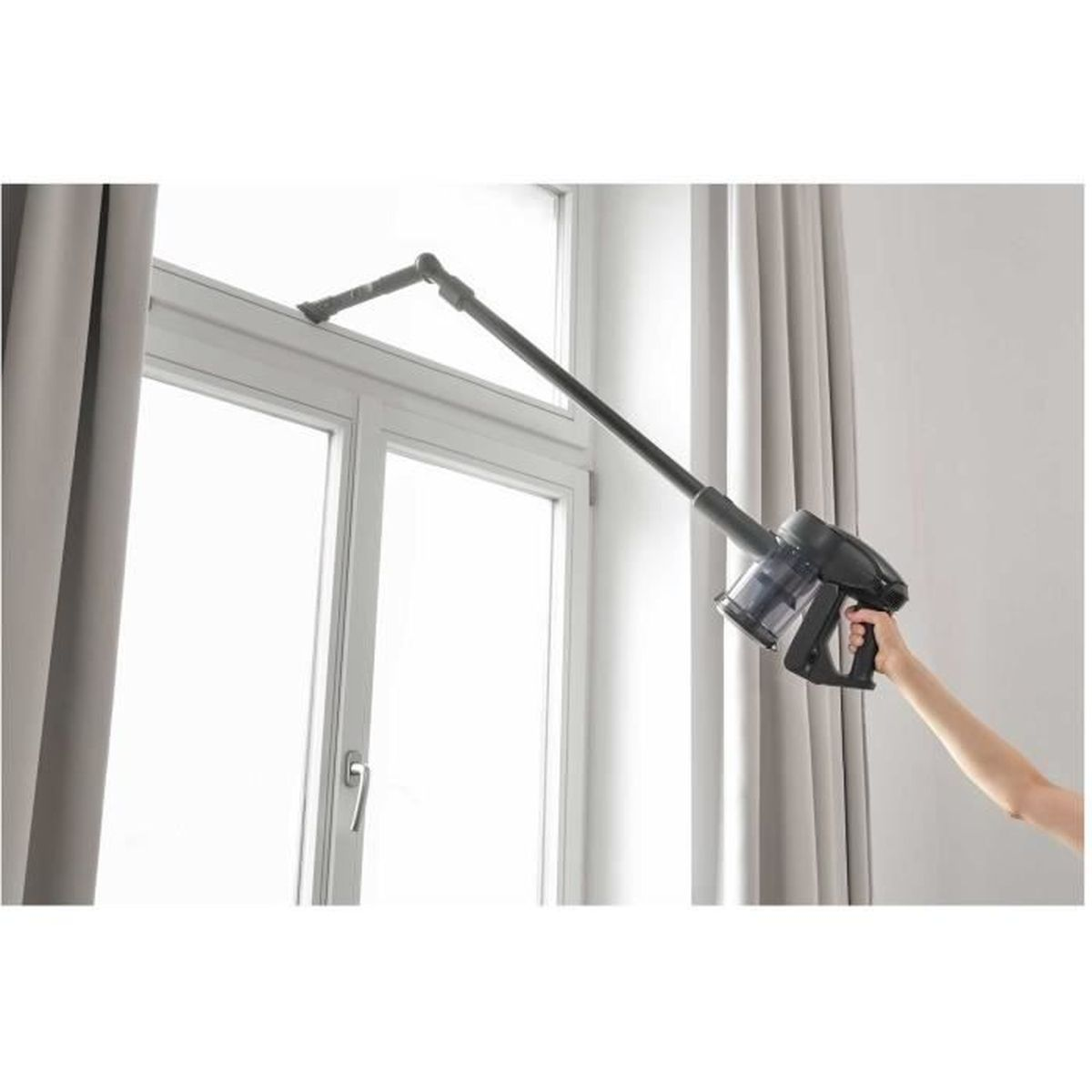 Ein schwarzer Handstaubsauger mit Verlängerungsrohr reinigt einen Fensterrahmen.