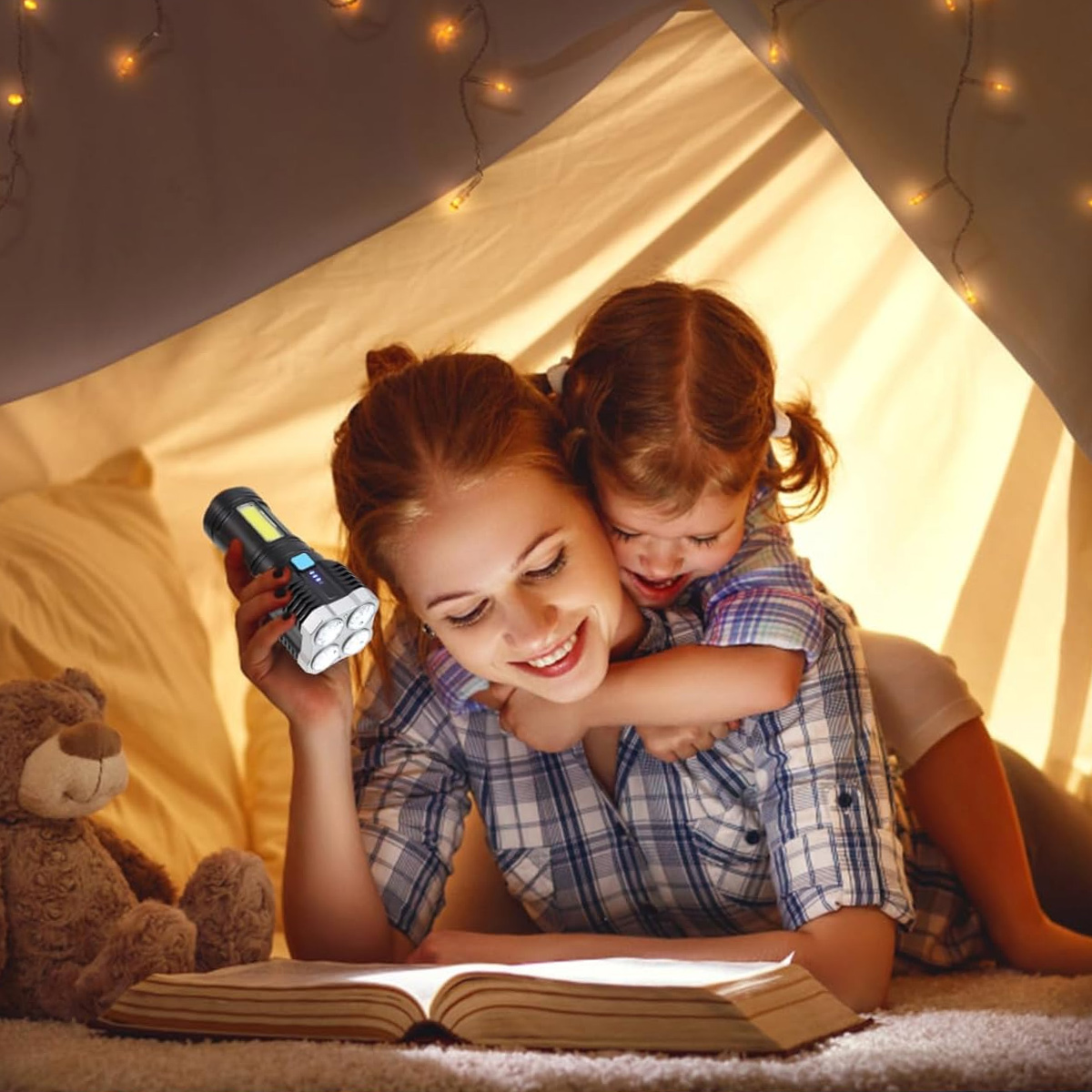Mutter und Kind lesen Buch in einem Zelt, beleuchtet von einer Taschenlampe.