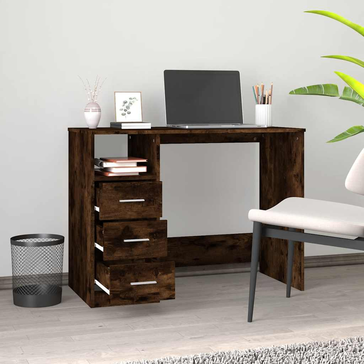 Ein dunkler Schreibtisch mit Laptop, Büchern, Stiften, Foto und Mülleimer.