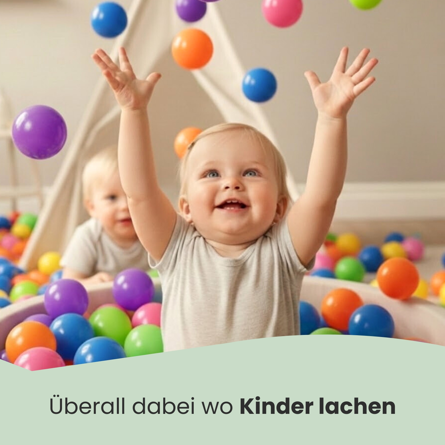Zwei Babys spielen mit bunten Bällen in einer Spielzeugkiste. Eines wirft Bälle.