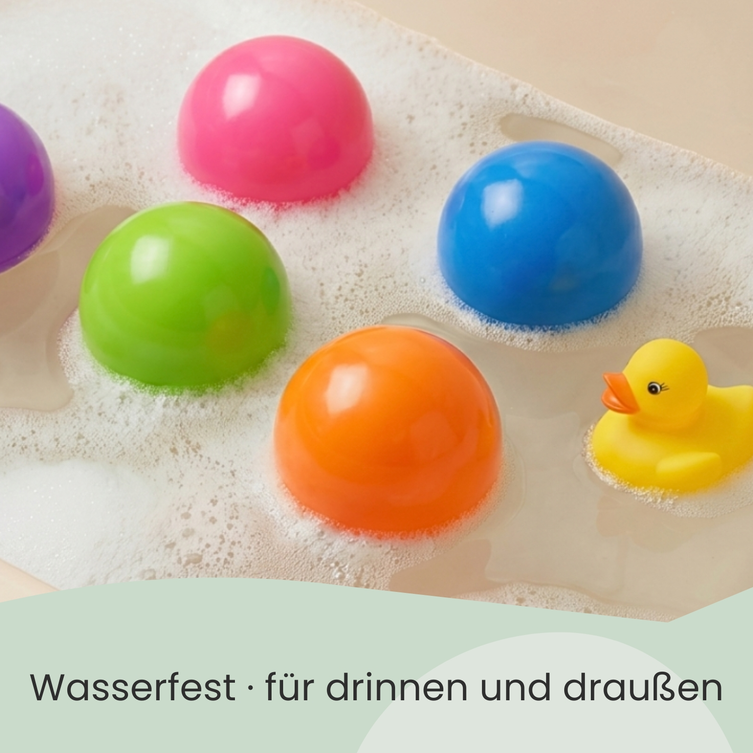 Bunte Bälle und eine gelbe Quietscheente in Schaum.