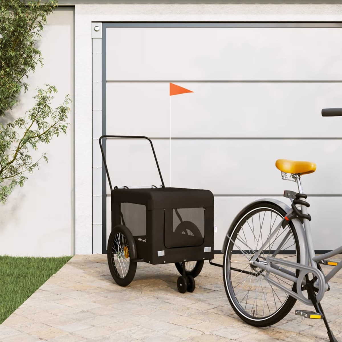 Ein graues Fahrrad mit gelbem Sattel steht neben einem schwarzen Haustieranhänger mit orangefarbener Flagge.
