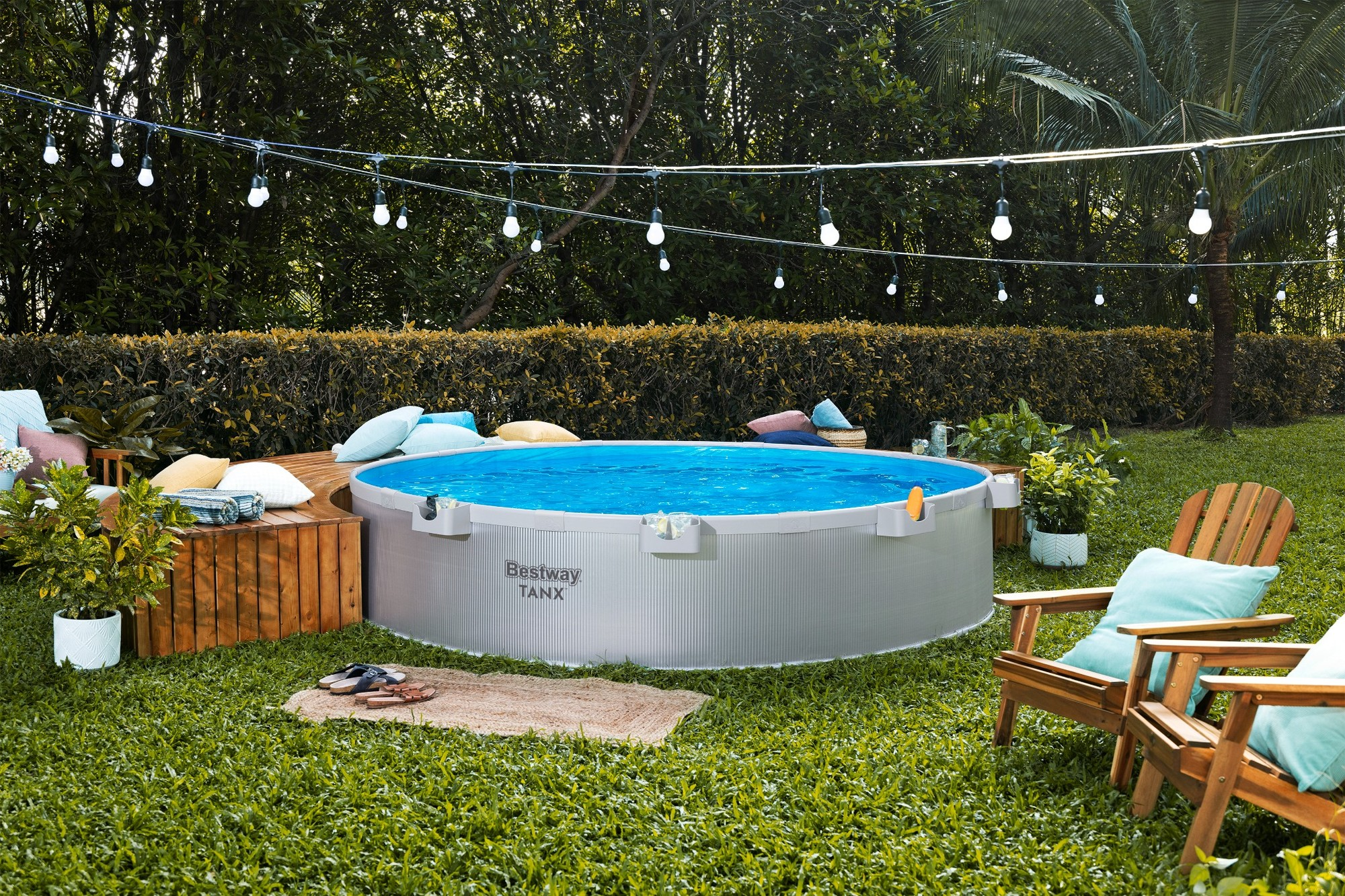Ein Gartenszene mit rundem Pool, Holzdeck, Stühlen und Lichterkette.