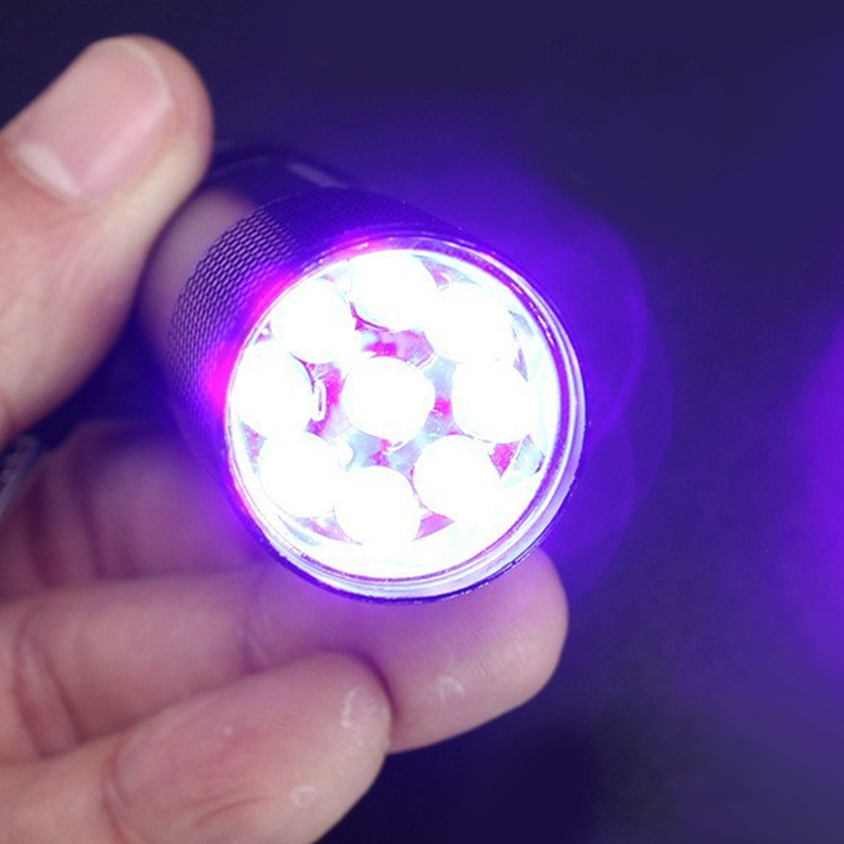 Eine Hand hält eine UV-Taschenlampe mit leuchtenden LEDs und violettem Licht.