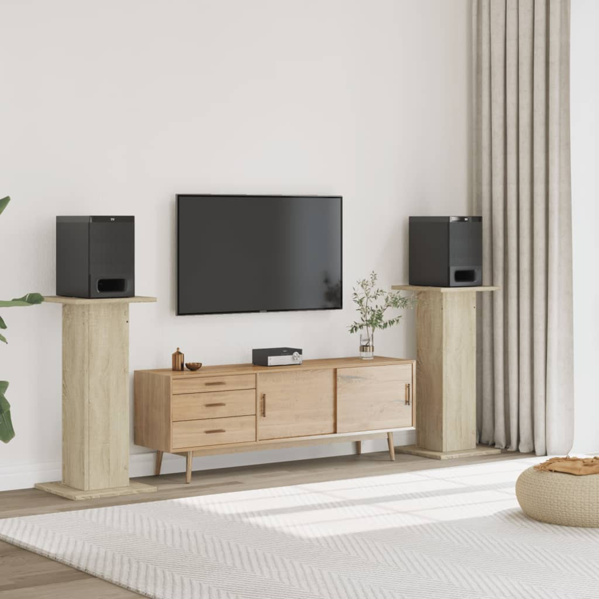 Schwarze Lautsprecher auf Holzsockeln neben einem Fernseher über einem Sideboard.
