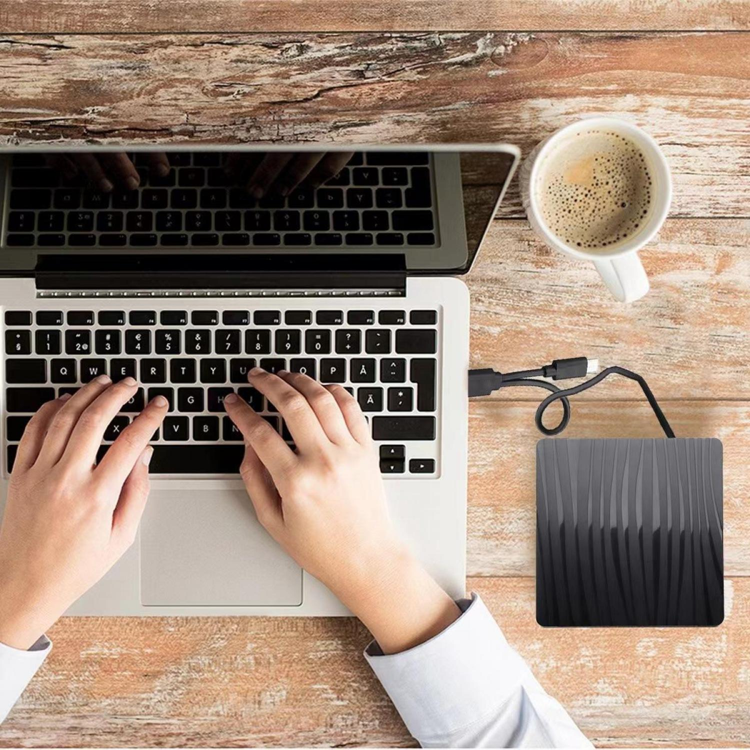 Person tippt auf Laptop, daneben eine Tasse Kaffee und externe Festplatte.