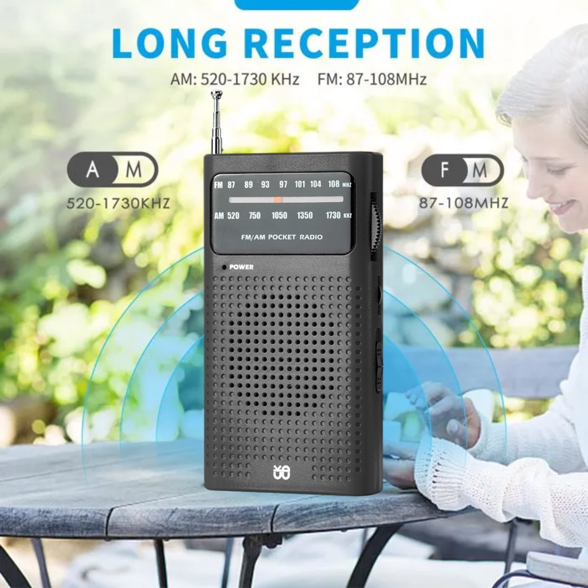 Ein schwarzes UKW/AM-Taschenradio mit Antenne steht auf einem Holztisch im Freien.