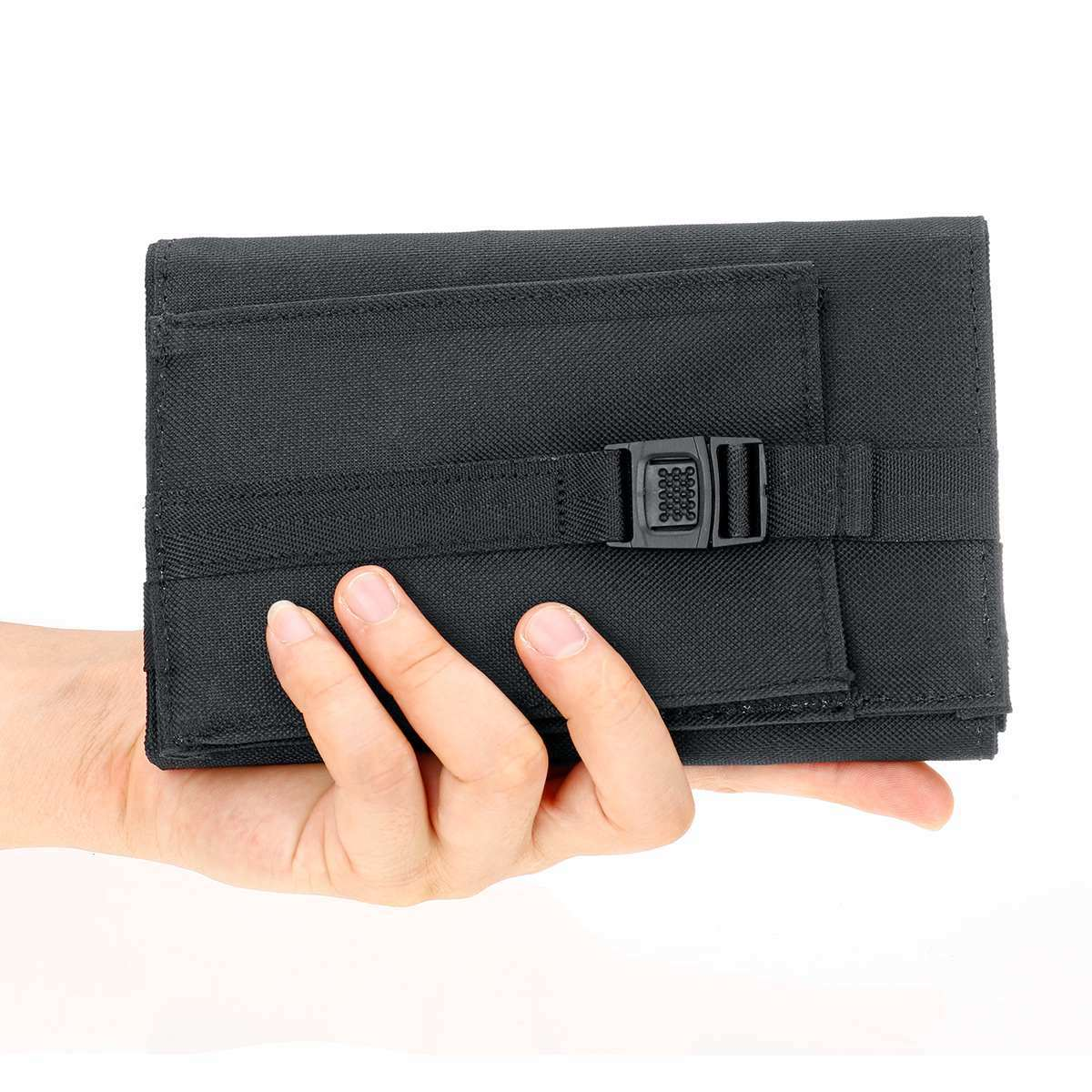 Eine schwarze Stofftasche mit Schnalle wird von einer Hand auf weißem Hintergrund gehalten.